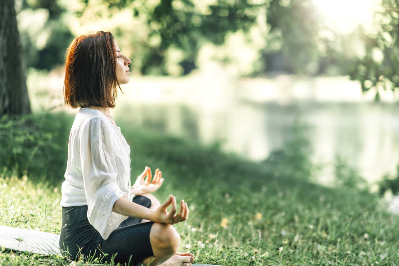 ormanda huzurla meditasyon yapan kısa saçlı genç kadın