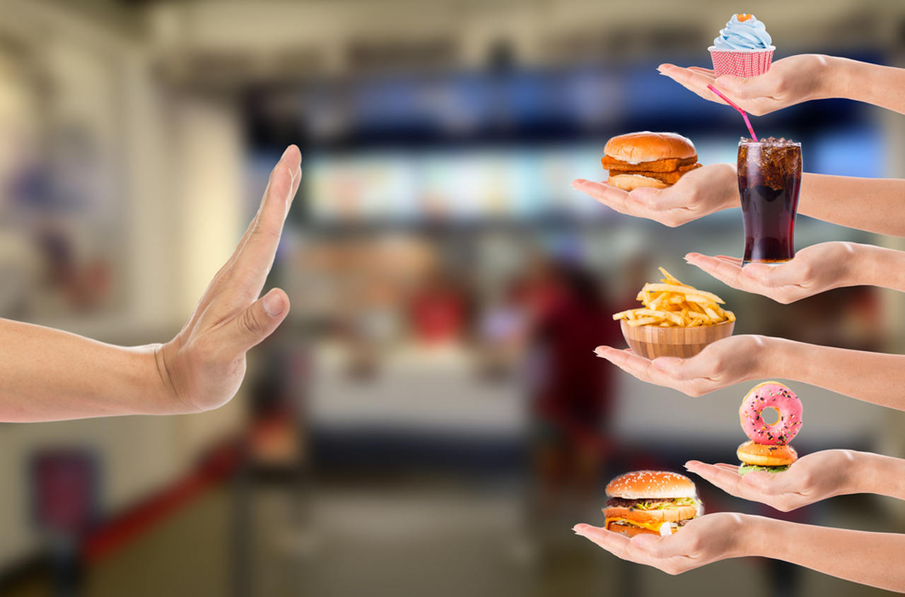sağ tarafta bulunan fast food besinlere hayır işareti yapan el