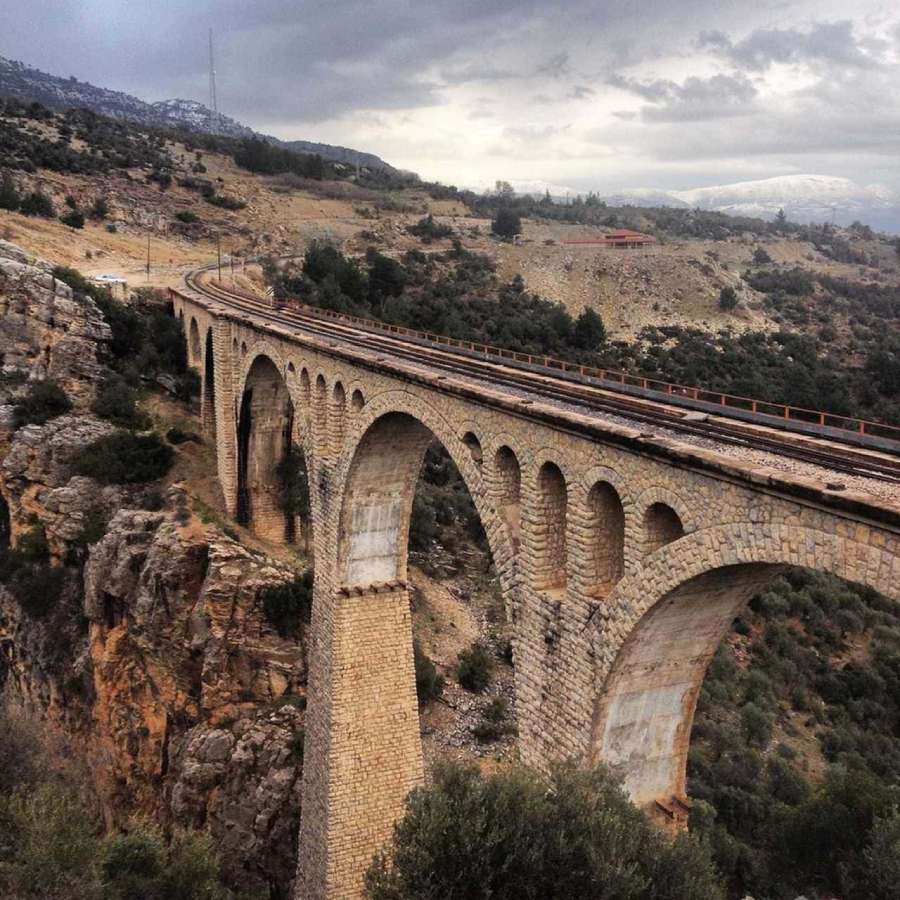 üzerinde tren yolu olan su kemelerinin ilerisinde görünen dağlar