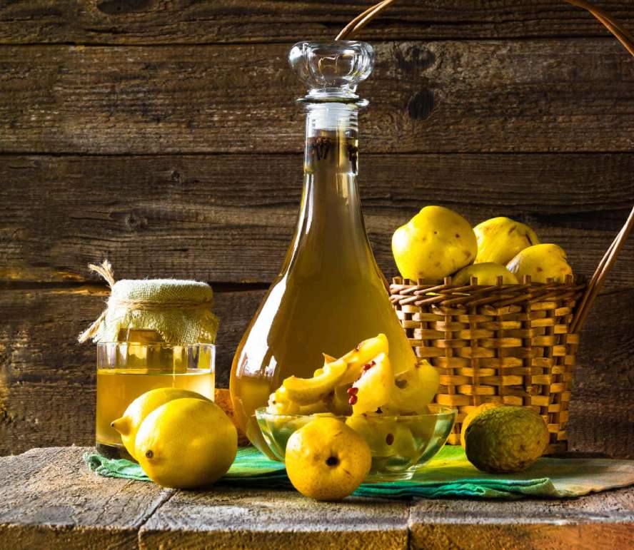 Sürahi ve kavanoz içinde duran ayva şerbeti ile ayva ve limonlar