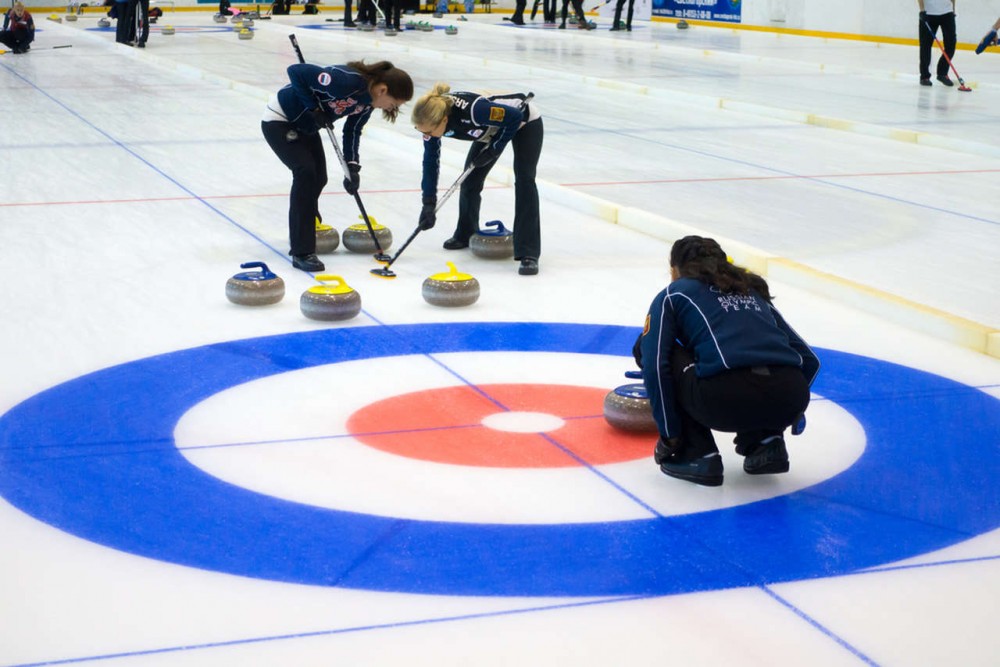 teams playing curling sport on ice