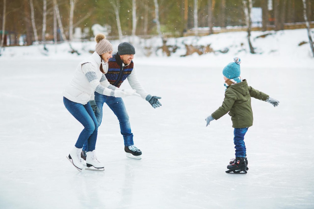 Family ice skating together in snowy weather