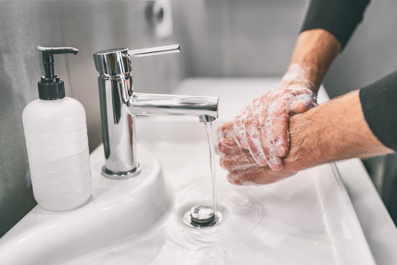 muslukta ellerini sabunlayarak yıkayan erkek
