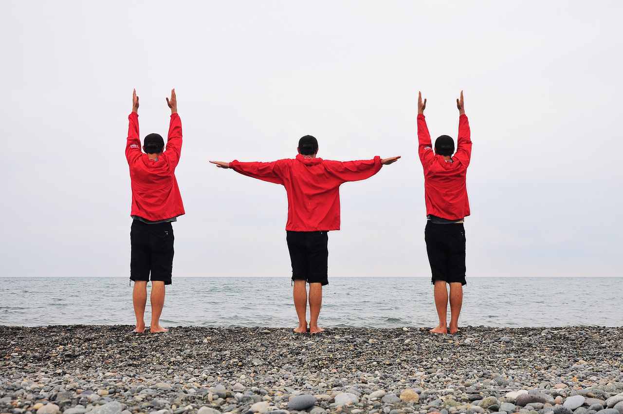 sahilde denize karşı egzersiz yapan 3 kişi