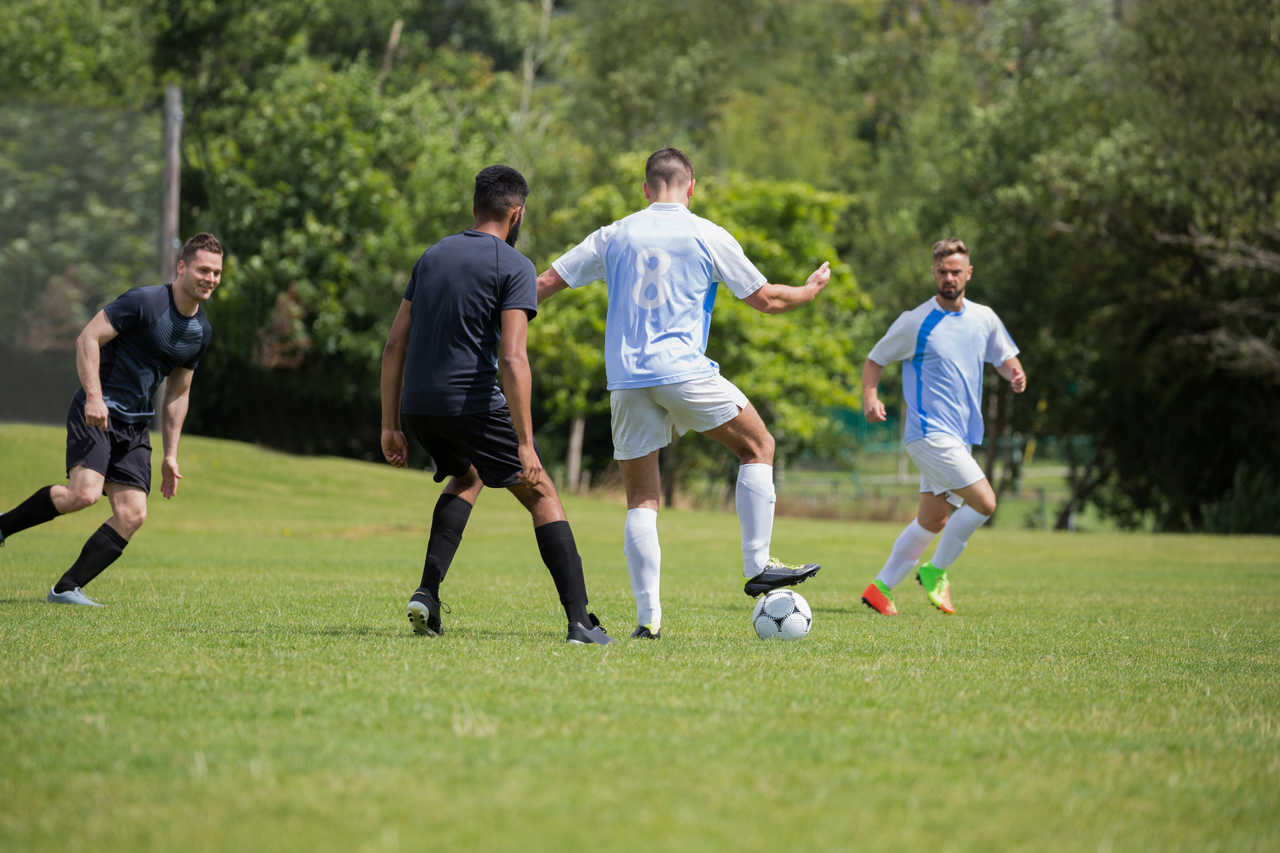 çim sahada futbol oynayan futbolcular