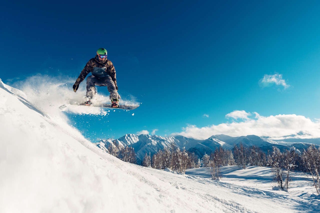 karlı bir dağda snowboard yapan adam