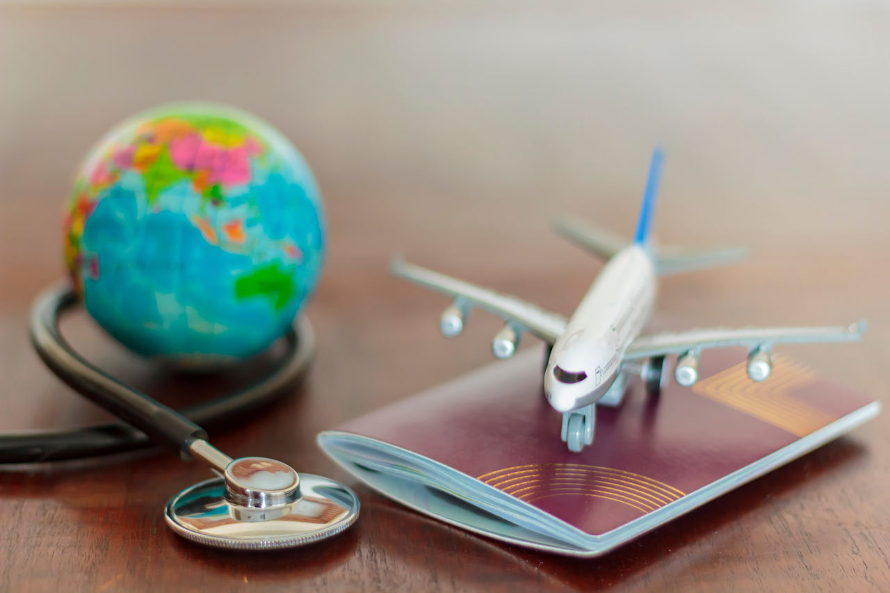 Masa üzerinde duran maket uçak, pasaport, steteskop ve yerküre