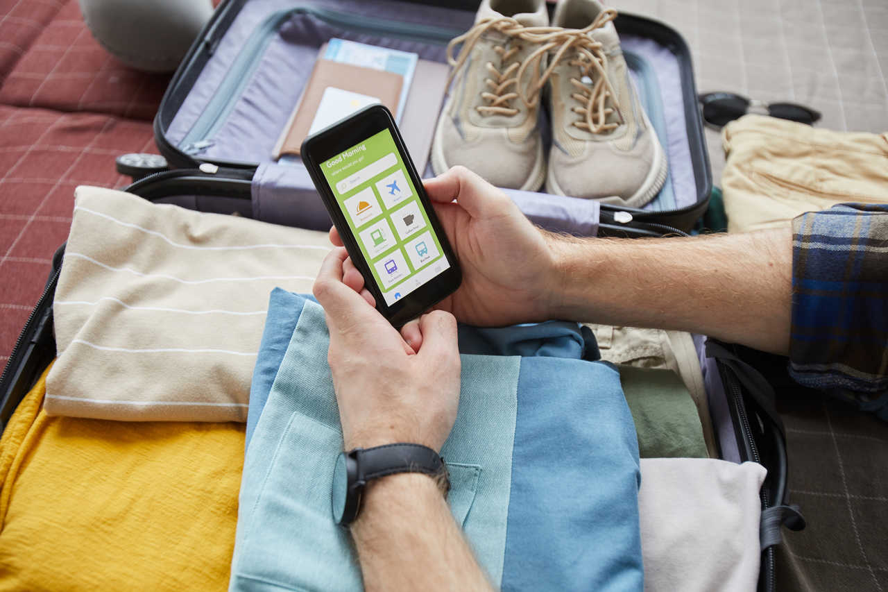 seyahat uygulamaları arasından pack checklist ile bavulundaki eşyaları kontrol eden adam