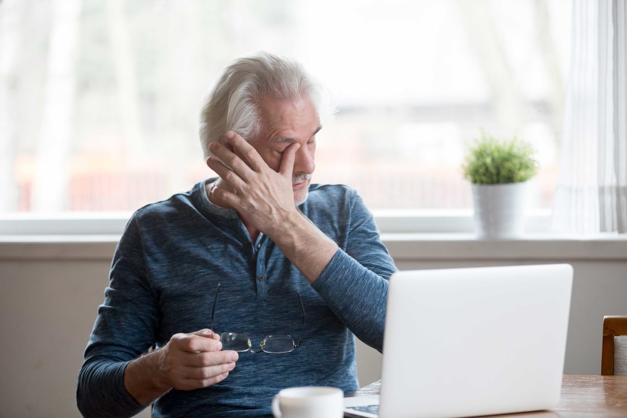 Bilgisayar başında fiziksel yorgunluk yaşayan ve vitamin eksikliği belirtileri gösteren yaşlı adam