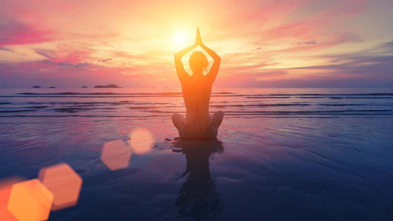 Gün batımında yoga yapan kadın