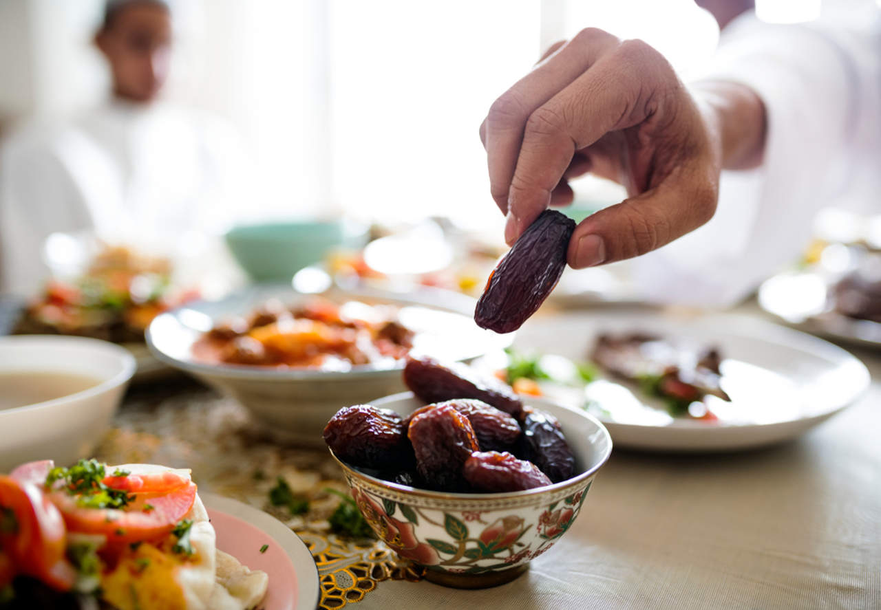 iftar sofrasında hurmayı eli ile tutan adam 