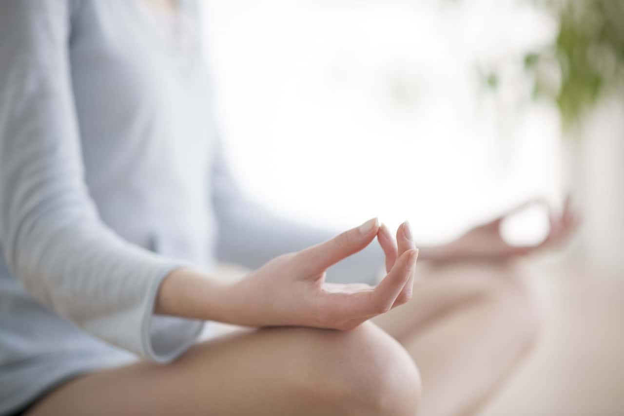 Parmaklarını dizinde birleştirerek yoga yapan kadın