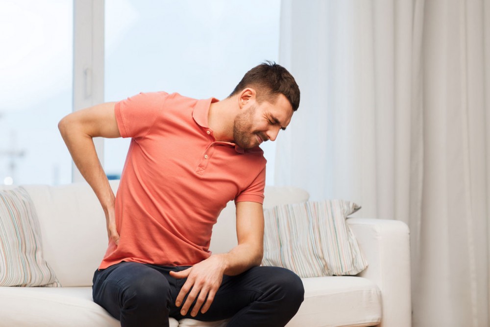 red shirted man who suffers back pain