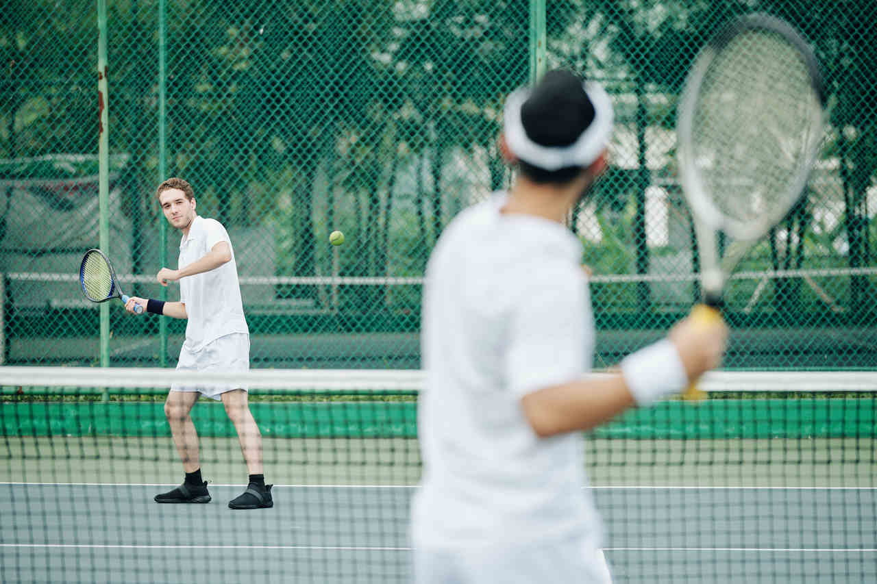 Kort içerisinde tenis oynayan insanlar