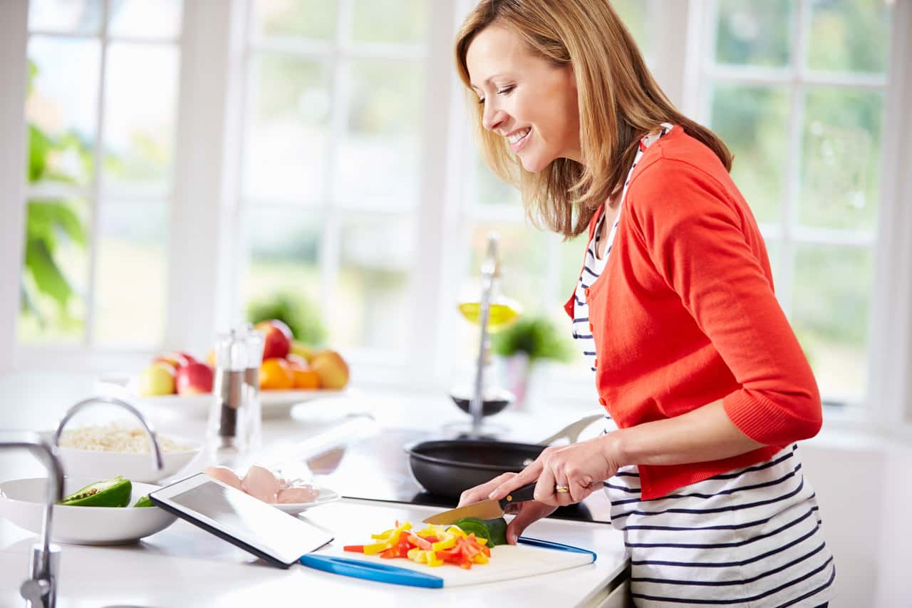 Mutfakta tabletine bakaran yemek tarifi yapan mutlu kadın