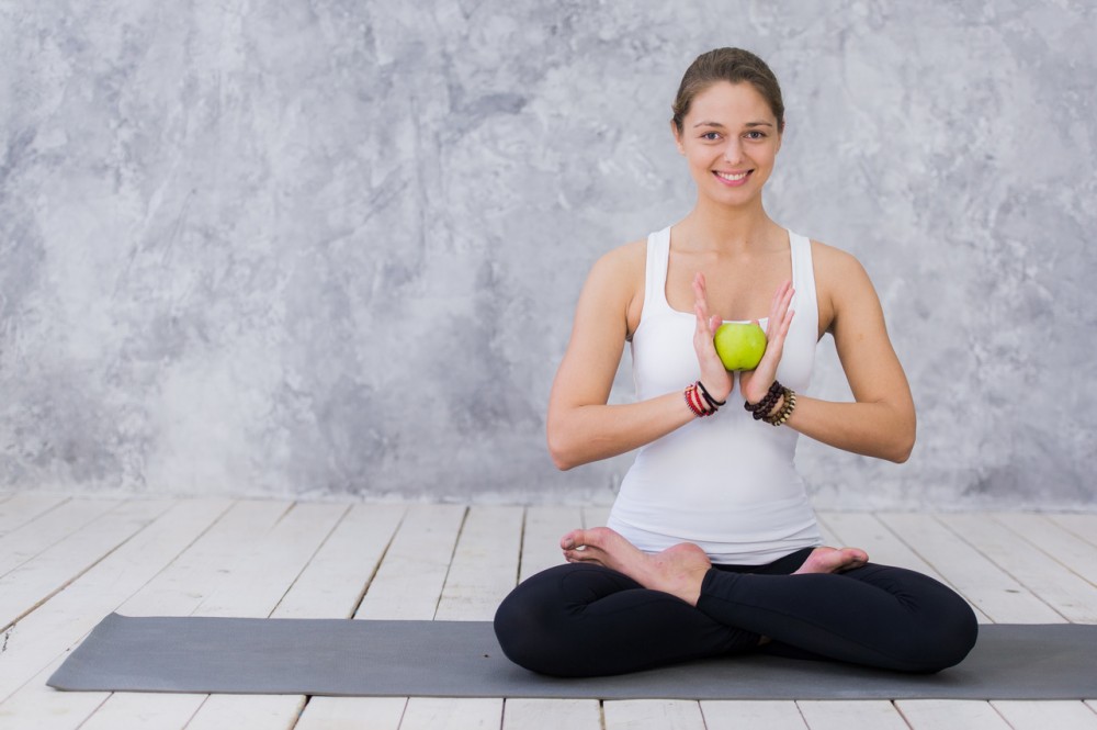 yoga yapan ve elinde elma tutan kadın